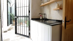 Una cocina con encimera negra, armarios blancos y una reja de metal que da a un patio.