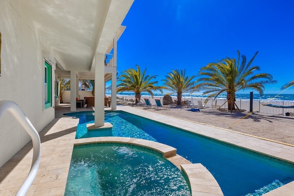 A swimming pool with a view of the beach and palm trees.