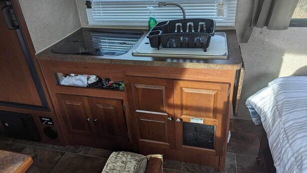 Une petite cuisine équipée comprenant un évier, une cuisinière et des placards de rangement.