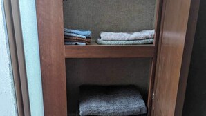 Un meuble en bois doté de trois étagères, chacune contenant des serviettes pliées.