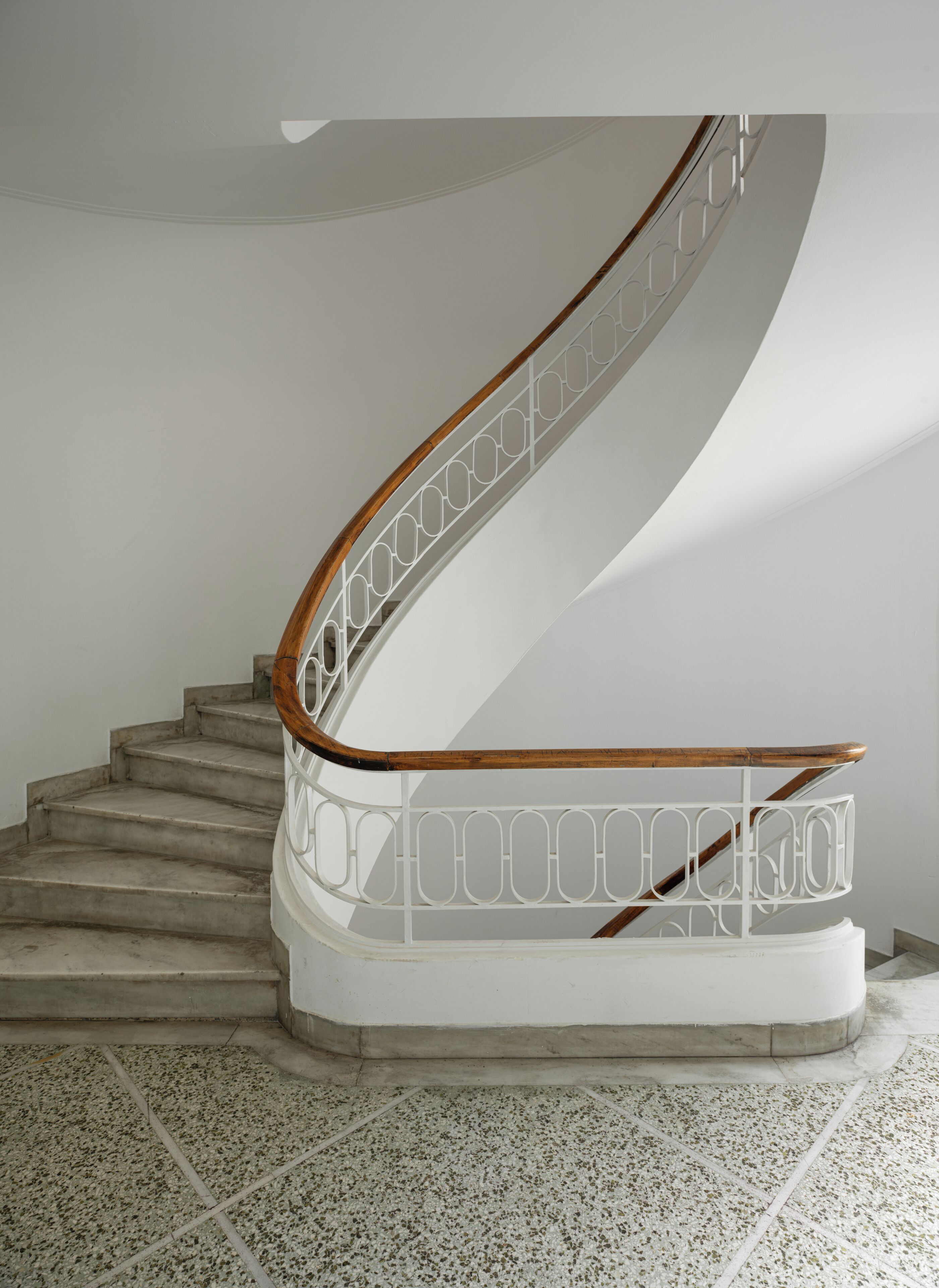 Eine Wendeltreppe mit hölzernem Geländer und weißer Balustrade.