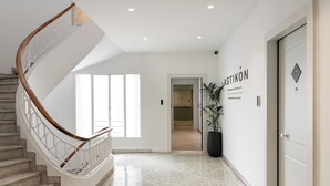 Um lobby de hotel moderno com uma escadaria de mármore, uma planta em vaso e uma placa com o nome 'ASTIKON'.
