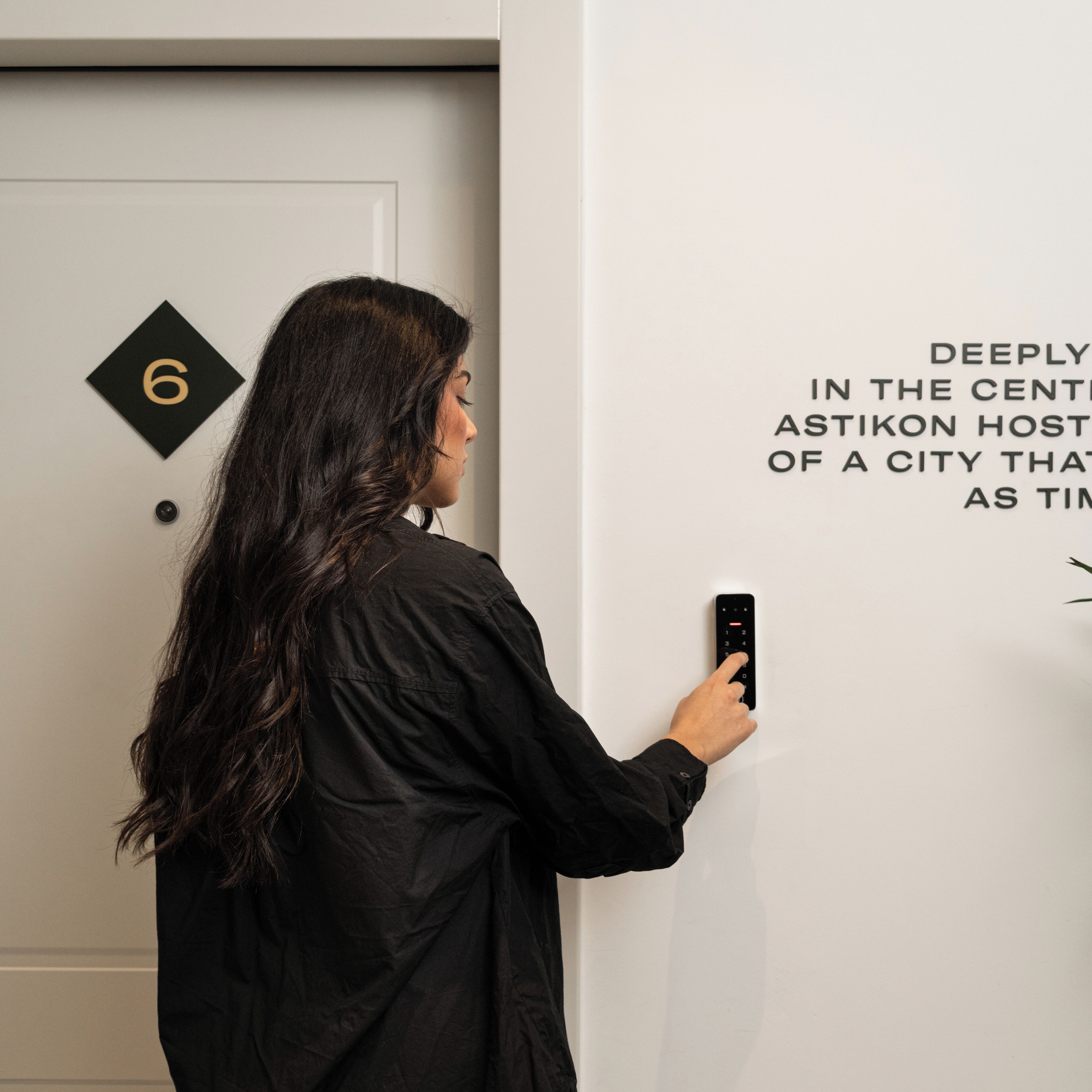 A person using a keycard to enter a room with a door marked with the number 6.