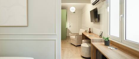 A modern hotel room with a bed, a desk, a chair, and a large window.