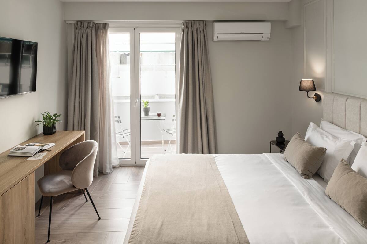 Ein modernes Hotelzimmer mit Bett, Schreibtisch, Stuhl und Fernseher.
