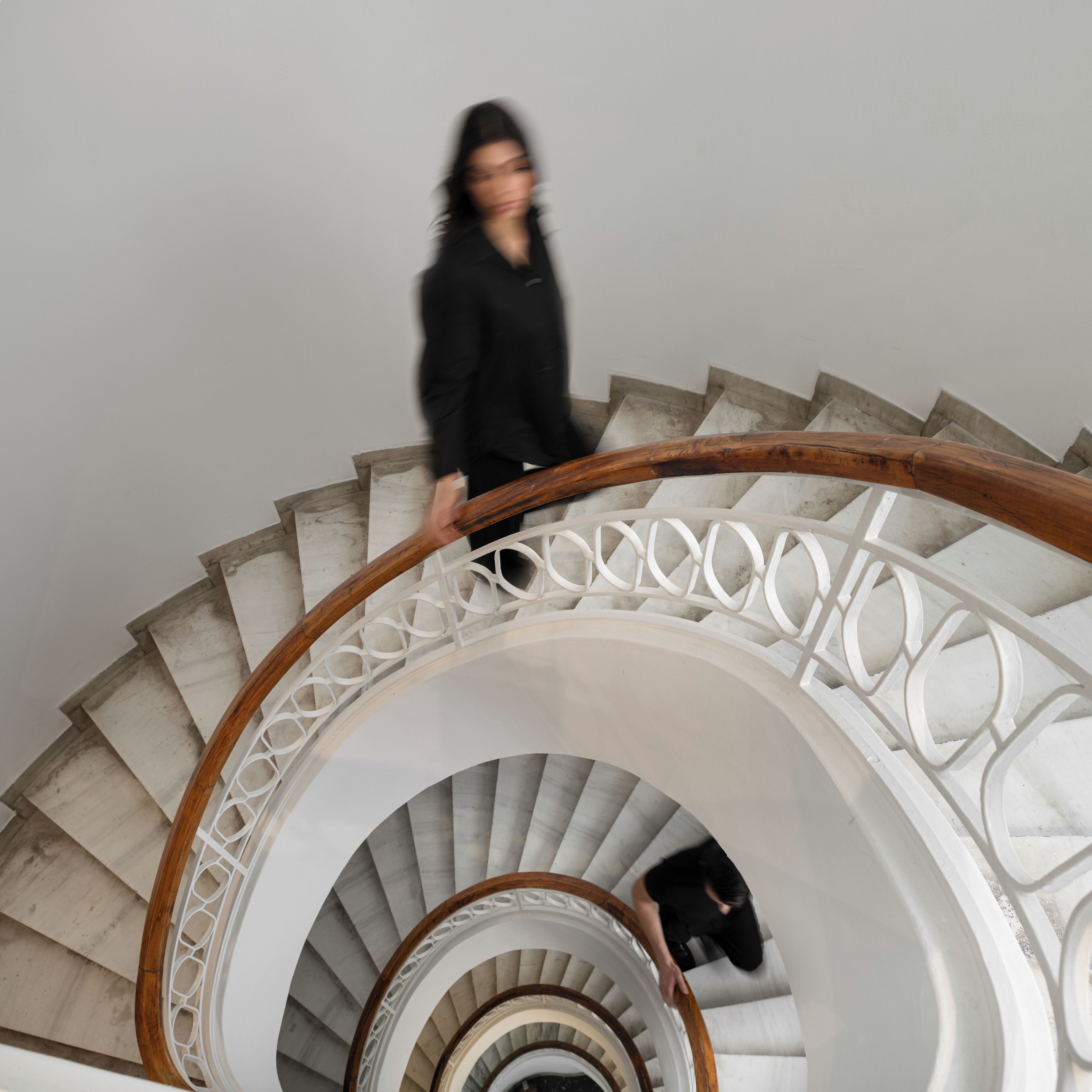 A spiral staircase with a wooden handrail and white balustrade.