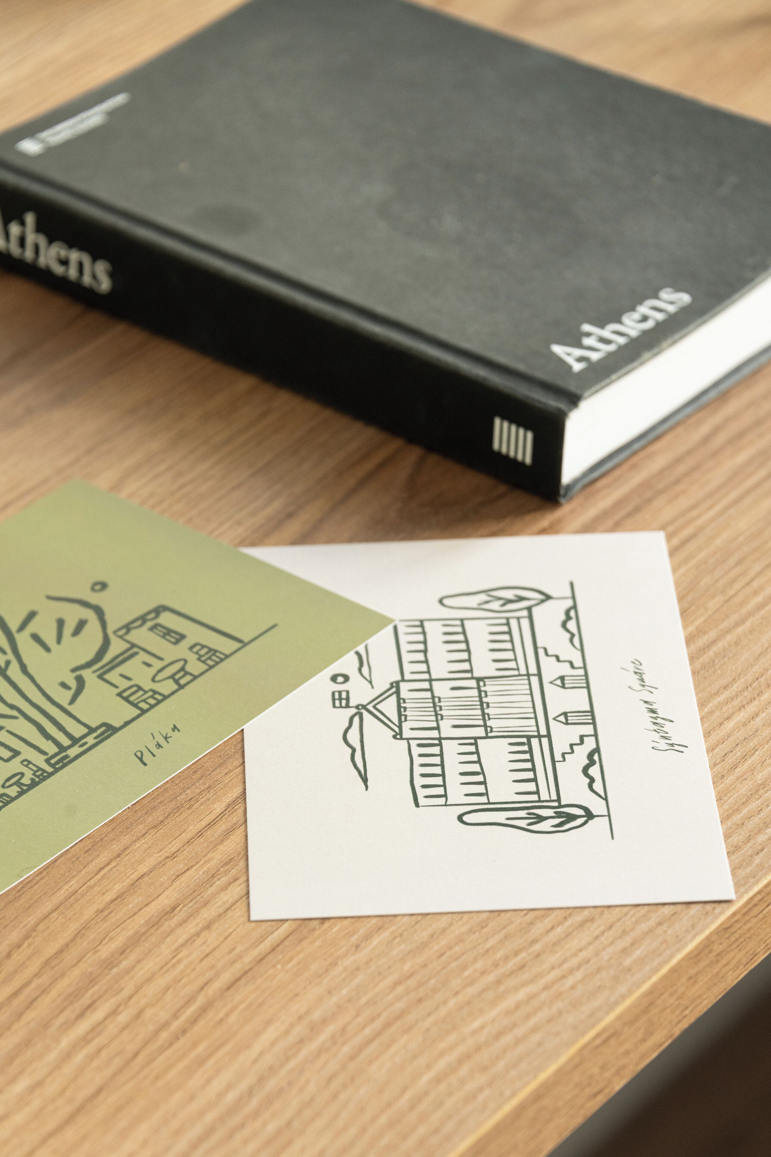 Ein Buch mit dem Titel 'Athens' und eine Postkarte mit einer Zeichnung eines Gebäudes.