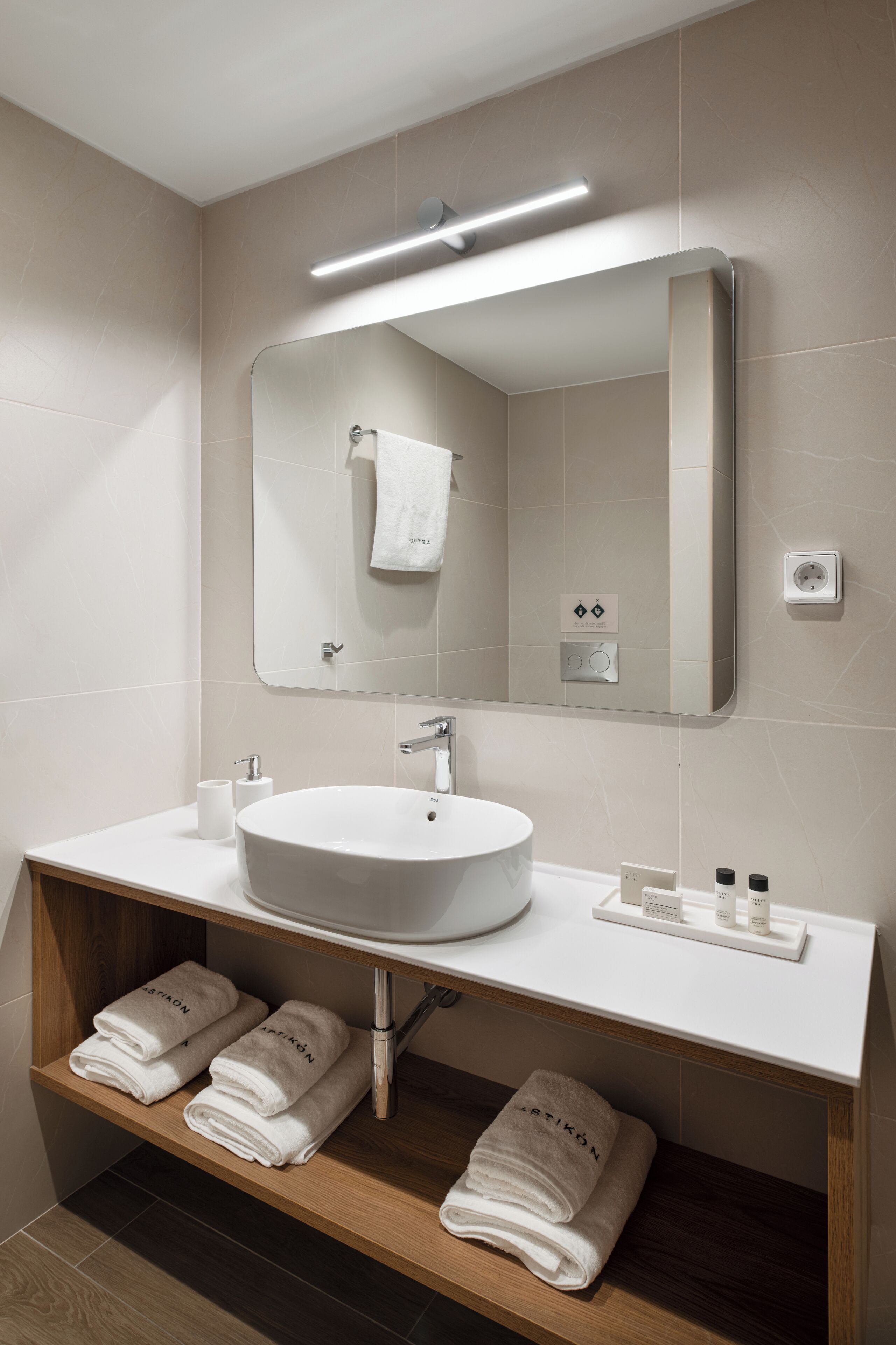 A modern bathroom with a white sink, mirror, and towel rack.