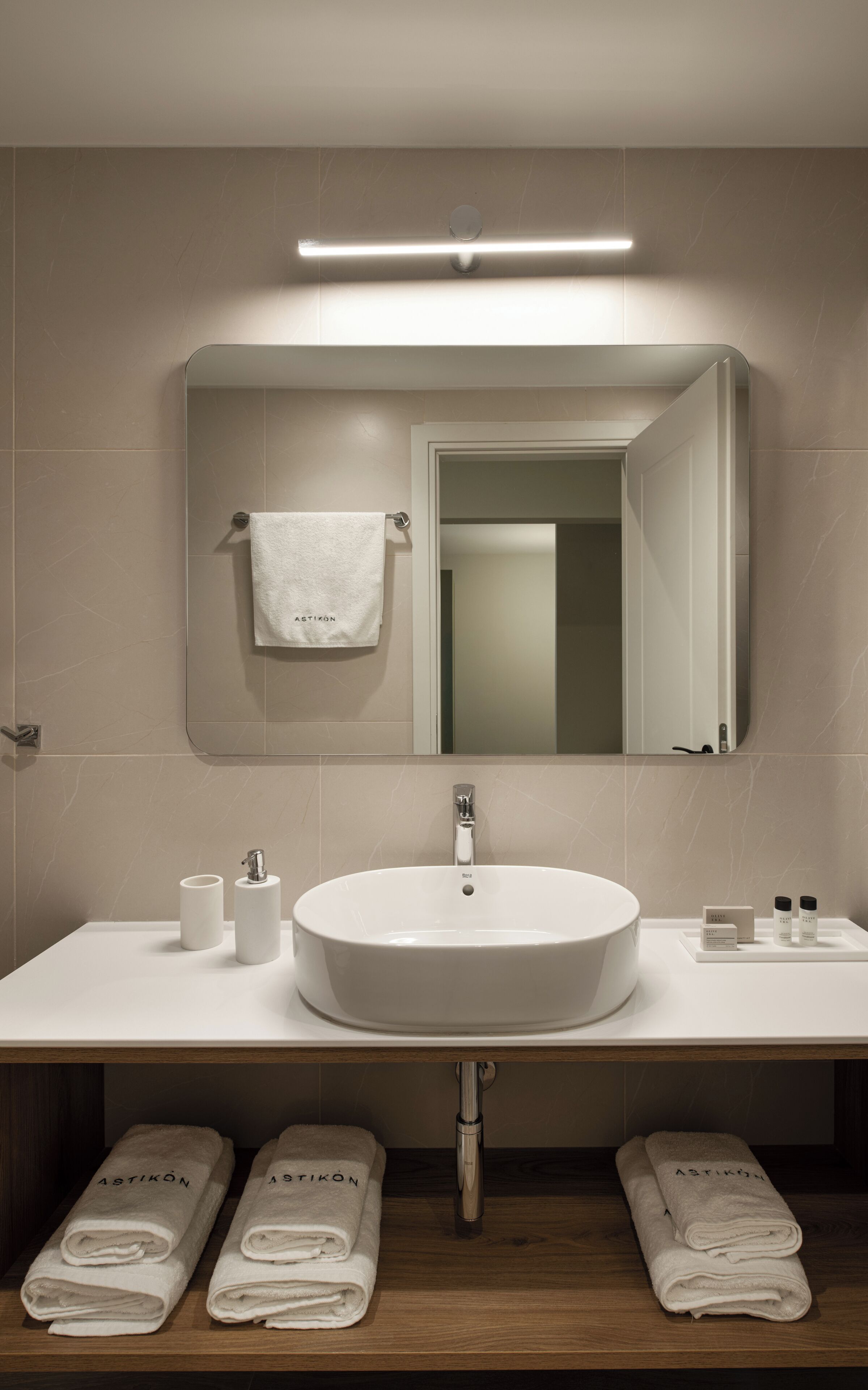 Een moderne badkamer met een grote wastafel, een spiegel en een handdoekrek.
