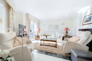 A modern living room with a sofa, armchairs, a coffee table, and a TV. - E04 Jardines 1 - Apartment (Sitio de Calahonda)