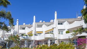 A white building with multiple balconies, satellite dishes, and potted plants. - L02 Jardines 1 - Apartment (Sitio de Calahonda)