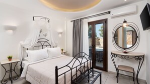 Un dormitorio con cama, mesitas de noche, tocador con espejo y televisor montado en la pared.