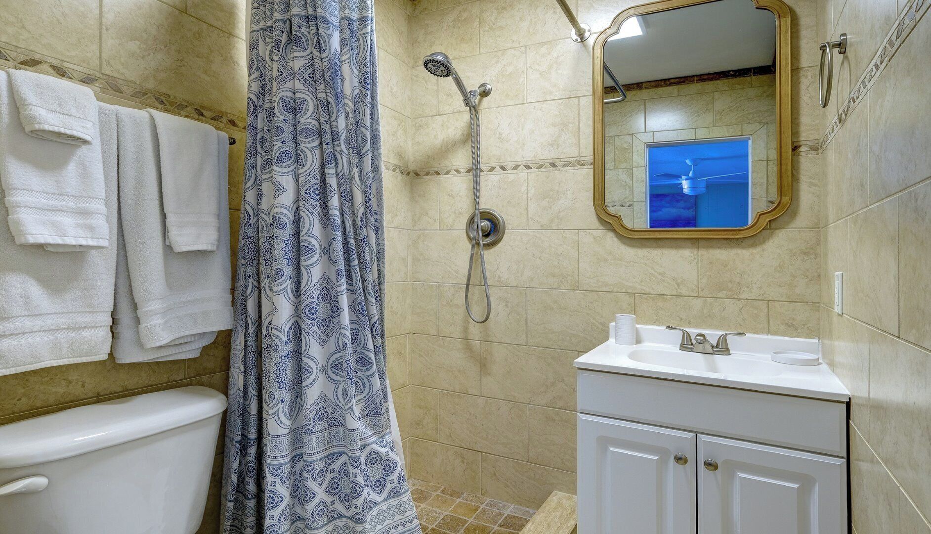 A bathroom with a shower, toilet, sink, and a mirror.