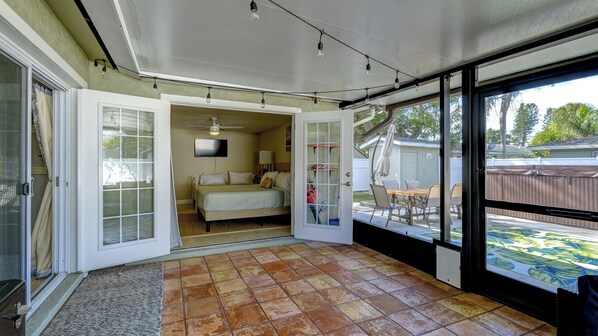 A room with a bed, a ceiling fan, and a view of the backyard.