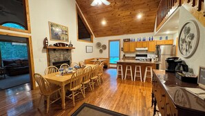 Une cuisine spacieuse avec des meubles en bois, un coin repas doté d’une grande table et de chaises, et un salon confortable avec une cheminée.