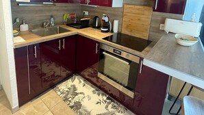 Una cocina moderna con armarios oscuros, horno empotrado y encimera de madera.