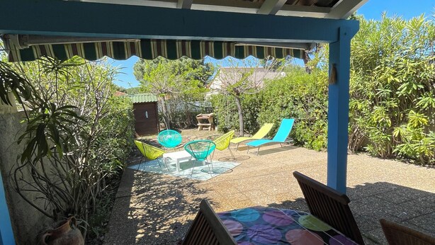 Un patio al aire libre con una mesa y sillas, rodeado de plantas en macetas y una vista del cielo.