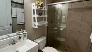 Ein Badezimmer mit Dusche, Toilette, Waschbecken und Spiegel.