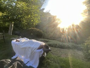 Guests can relax under the warm glow of the sun in a serene outdoor setting surrounded by lush greenery.