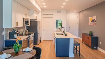 A modern kitchen with white cabinets, a central island, and a dining area with a table and chairs.