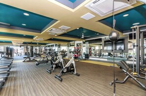 Une salle de sport équipée de machines de cardio, de matériel de musculation et de miroirs.