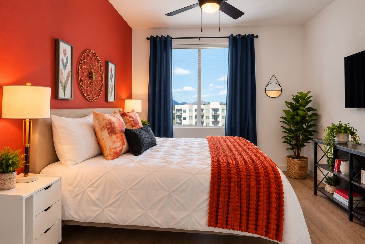 Quarto de hotel com cama, mesa de cabeceira, luminária, TV fixada na parede, janela com cortinas e vista para edifícios.