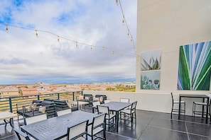 Une terrasse extérieure avec des tables et des chaises, des guirlandes lumineuses et des œuvres d’art accrochées au mur.