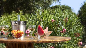 Une table en bois, sur laquelle se trouvent un panier de fruits, un récipient en métal et deux verres.