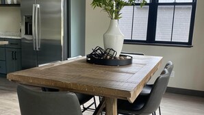 Eine moderne Küche mit einem eingebauten Kühlschrank, einem Esstisch mit Stühlen und einem Fenster mit Jalousien.
