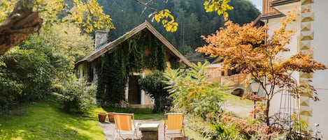 Eine rustikale Holzhütte mit geneigtem Dach, umgeben von üppigem Grün und einem gepflegten Garten.