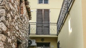 Ein schmaler Gang mit einer Steinmauer an einer Seite und einem gelben Gebäude mit einem Balkon an der anderen.