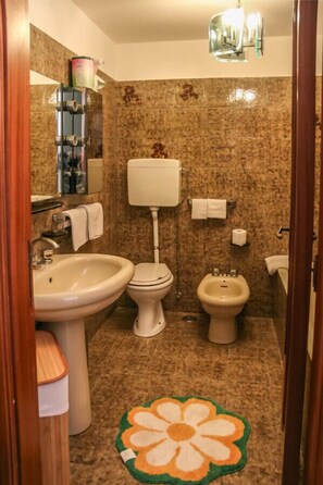 Une salle de bain comprenant des toilettes, un bidet, un lavabo et un miroir.