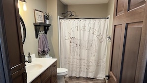 A bathroom with a wooden vanity, a toilet, and a shower curtain with a cow design. - Quiet place on the prairie near Wessington, SD.  (Wessington)