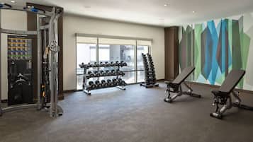 A gym with weightlifting equipment, dumbbells, and benches.