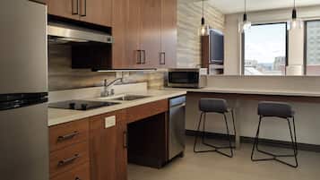 A modern kitchen with wooden cabinets, stainless steel appliances, a microwave, and two bar stools.