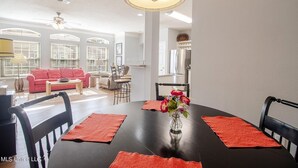 A dining area with a black table, red placemats, and a vase of flowers.