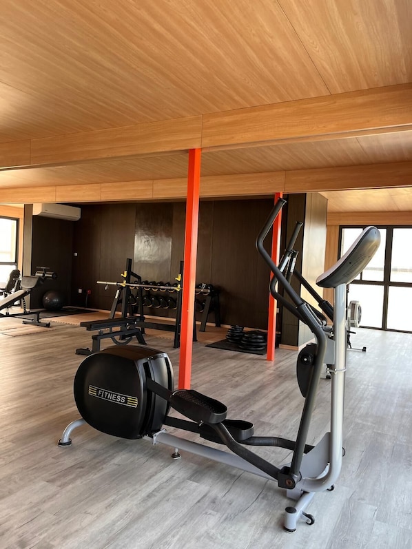 A gym with exercise equipment, wooden flooring, and large windows. - Calypso Hotel Nevis (Camps)