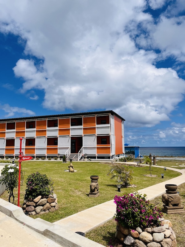 A modern building with a flat roof, multiple balconies, and a view of the ocean. - Calypso Hotel Nevis (Camps)