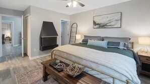 A bedroom with a bed, a ceiling fan, a fireplace, and a painting on the wall. - Hot Tub, Game Room, Near SU, sleeps 10 (Syracuse)