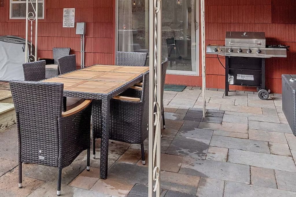 An outdoor patio with wicker furniture, a wooden table, and a grill.