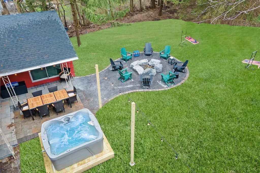 A backyard with a hot tub, a fire pit, and outdoor seating.