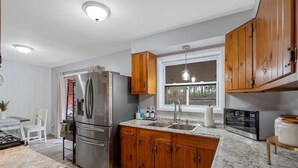 A modern kitchen with wooden cabinets, stainless steel appliances, and a granite countertop. - Hot Tub, Game Room, Near SU, sleeps 10 (Syracuse)