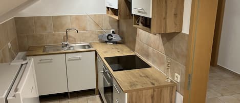 A compact kitchen with a sink, stove, and cabinets.