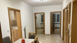 Un comedor con una mesa y sillas, un radiador, y una cocina visible a través de una puerta abierta.