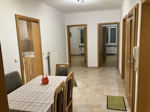 A dining area with a table and chairs, a radiator, and a kitchen visible through an open door. - Geräumige Ferienwohnung in Ruhiger Lage Nahe Ingolstadt (Hepberg)