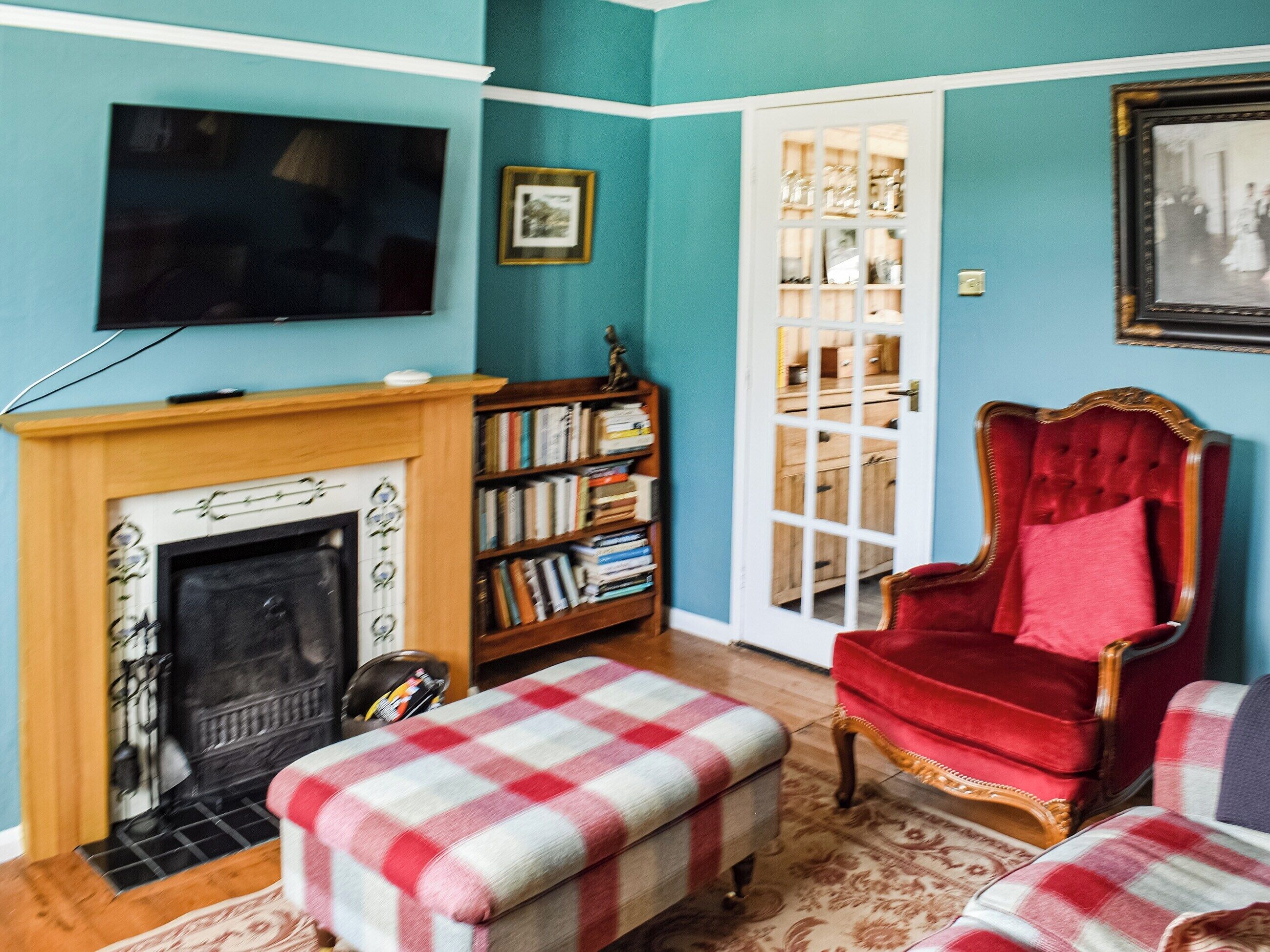 Ein Wohnzimmer mit Kamin, Fernseher, Bücherregal und einem roten Sessel.
