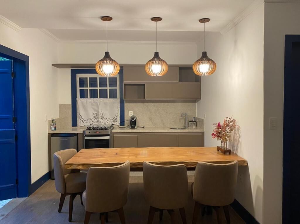 A modern kitchen with a wooden dining table and four chairs, a blue door, and pendant lights above the counter.