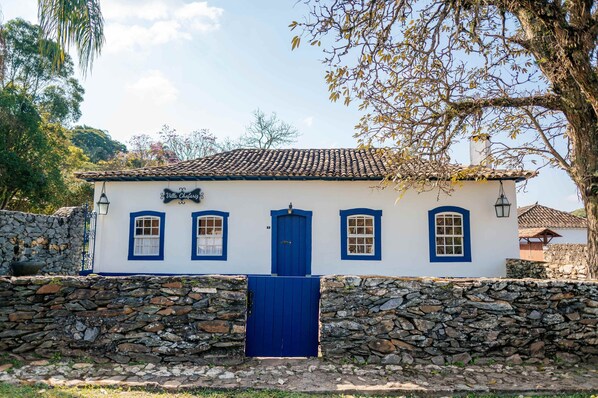A white building with blue accents, a stone wall, and a blue gate.