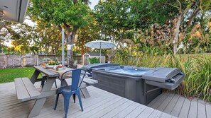 A deck with a hot tub, a picnic table, and chairs. - Hot Tub, Firepit, Deck | 10mins to Beach | Middle Terrace Cottage by AvantStay (Fort Lauderdale)