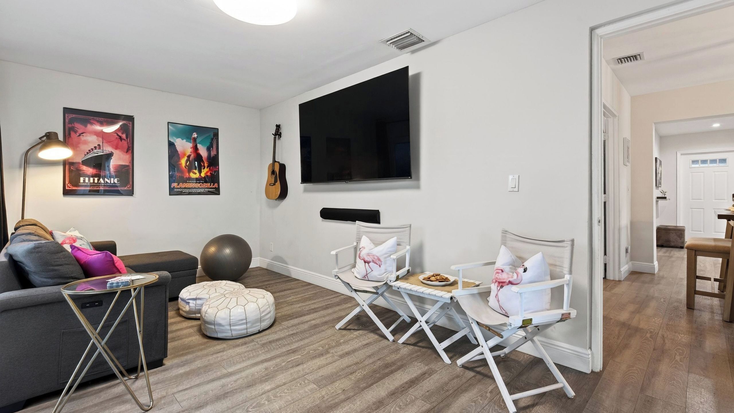 Een woonkamer met een bank, een salontafel, een televisie en een gitaar aan de muur.
